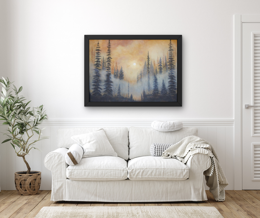 A framed landscape art print depicting a misty pine forest at sunset, displayed on a white wall above a white sofa in a styled living room.