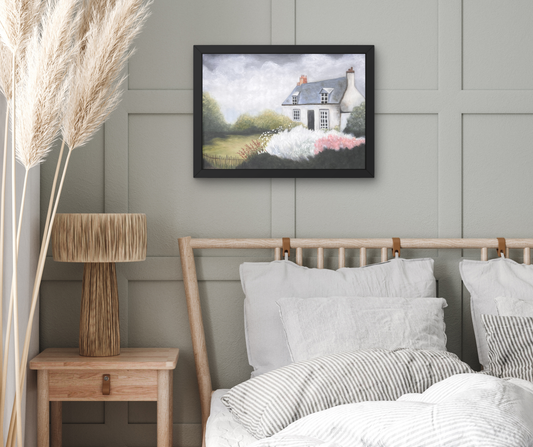 A framed landscape painting of a cottage in a field hangs on a gray paneled wall above a bed with white and gray striped bedding in a styled bedroom setting.