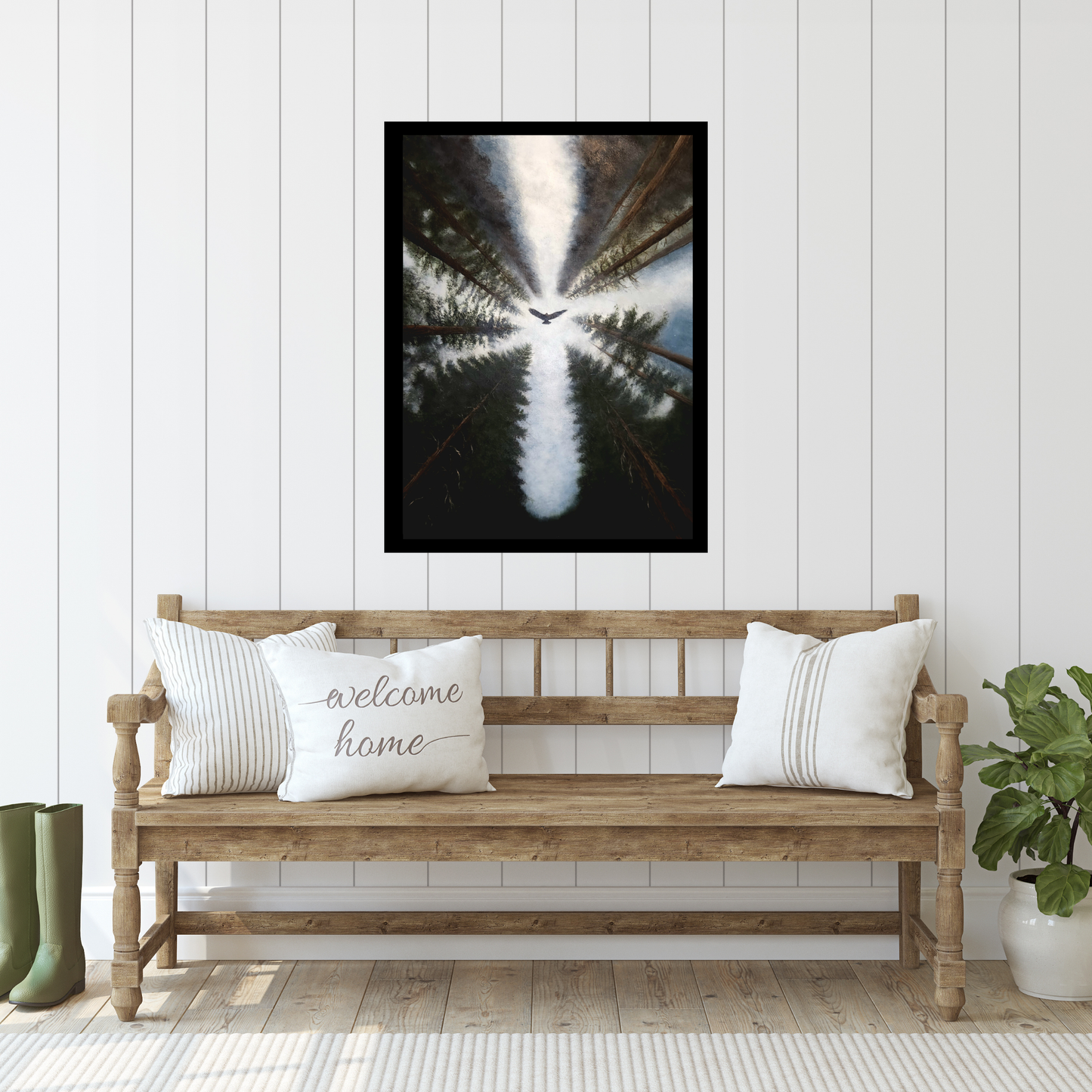 A framed vertical art print depicting a bird flying over a forest reflection, styled on a white paneled wall above a wooden bench with decorative pillows.