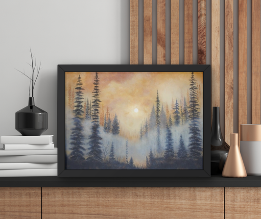 A framed landscape art print depicting a misty pine forest at sunrise or sunset, styled on a wooden console table next to decorative vases and books.